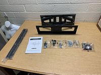 Show mount components laid out including wall mount arms, screws, spacers, and instruction manual.