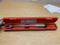 Torque wrench open in orange case on a table.
