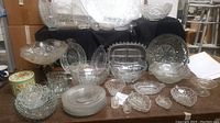 Wide angle view of entire lot showing the vintage cut glass bowls, dishes, platters, various shapes and sizes arranged on table