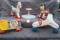 Five vintage Fisher Price ride on toys arranged on a cloth background showcasing wear and fading