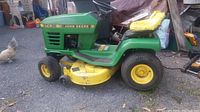 Side view of John Deere STX38 riding mower showing yellow mower deck and yellow seat.