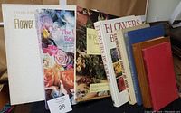 Photo showing a row of nine large flower arrangement books including titles on roses and wreaths, with various cover colors and floral images.