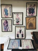 View of all seven framed swimsuit model prints hanging on a white wall above furniture.