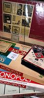 Photo showing several vintage Monopoly game boards, boxes, and game money bills spread out flat
