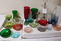 Lot of 25 vintage colored glassware pieces including vases, bowls, tumblers, and a three-tier serving tray in multiple colors.