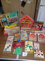 Photo showing the vintage puzzles and games on a table, including jigsaw puzzles and boxed games with distinctive retro packaging taken from a distance.