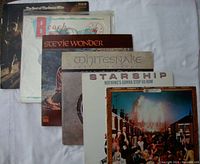 Five vinyl album covers laid out flat, showing The Beach Boys, Stevie Wonder, Whitesnake, Starship, and ELO albums.
