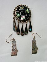 Full view of silver brooch with five hanging teardrops and matching silver earrings on white background to show design and condition