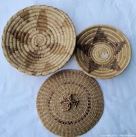 Three woven Native American baskets arranged on white background showing front and top views with natural woven patterns.
