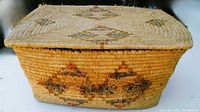 Exterior side view of rectangular woven basket showing geometric diamond woven patterns, wear and fiber fraying