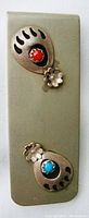 Front photo showing silver money clip with bear claw shaped settings inset with turquoise and coral stones and small silver flower decorations.