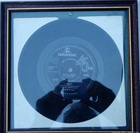 Framed original 45 RPM vinyl single by The Beatles with Parlophone label, showing the song "Help!" and released in 1965, inside a black and gold frame.