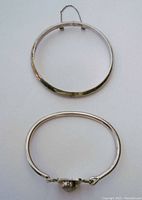 Two silver bracelets laid flat, showing overall shape and clasp chain