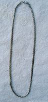 Full length view of the silver chain necklace laid out on a white surface.