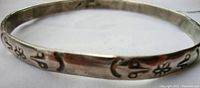 Close-up of Native American style sterling silver bracelet with etched floral and crescent moon designs.