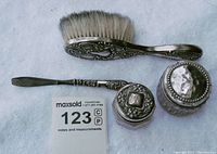 Overall group shot of the antique sterling silver beauty tools with brush, tweezers, and two crystal jars with silver lids.