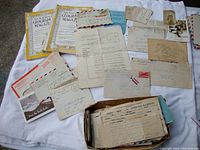 Overview photo showing assortment of letters, postcards, documents, and two National Geographic magazines spread out on a white cloth.