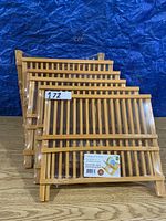 Six wooden folding dish racks stacked together, showcasing the slatted wood design and folding legs.