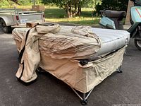 Photo showing the air mattress set up on a collapsible metal frame, covered with a fabric patterned cover and the carrying bag draped on the mattress.