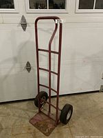 Full view of the metal dolly standing upright showing frame, base plate and wheels.