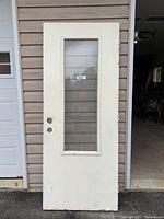 Front view of the white exterior door with glass insert showing its overall shape and condition