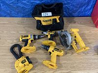 Overall view of DeWalt tool bag, five cordless power tools and dust extraction adapter with hoses laid on wood floor