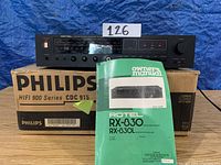 Full front view of the Rotel RX-830 receiver placed on top of a Philips box, with owner's manual in front.
