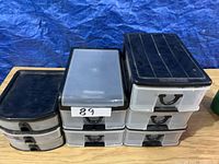 Front view of six small plastic drawer storage units on wooden surface with blue fabric background.