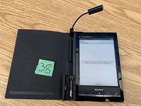 Sony e-Book Reader inside black protective cover, device screen displaying empty book menu, flexible LED reading light attached above screen.