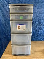 Front view of a 5-drawer clear plastic storage container with beige trim and handles