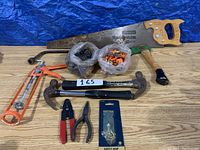 Overview photo showing various hand tools including saw, hammers, pliers, pipe wrench handle, hammer drill bit, and safety hasp.
