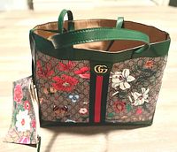 Front and exterior side of the large tote purse showcasing the floral print, double G logo emblem, and green leather handles.