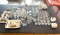 Top view showing large assortment of clear glassware, stemware, porcelain cups, trays, and small decorated containers.