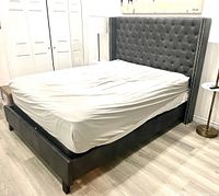 Front three-quarter view of the bed frame with tufted headboard, side rails and footboard