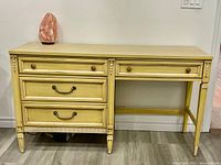 Front view of the vintage wooden desk with four drawers and a distressed cream finish.