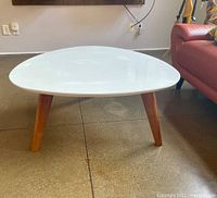 Front angled view of the white coffee table showing the top and wooden legs.