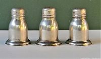 Front view of three Birks sterling silver salt shakers showing tapered shape and round base