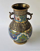 Front angle of twin handled brass vase showing painted cloisonne enamel with floral and abstract motifs.