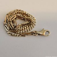 Coiled gold chain bracelet showing lobster clasp and link pattern on white background