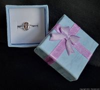 Photo showing the 10kt white gold child's ring with hollowed out cross in a small light blue gift box with pink ribbon bow.