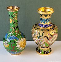 Two small cloisonne vases, green and gold, displayed side-by-side with floral cloisonne enamel designs.