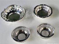 All four small vintage sterling silver dishes displayed on white surface, showing details and relative size