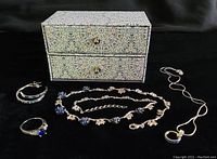 Photo showing the entire set laid out including earrings, ring, necklace, pendant necklace, and gift box against black background