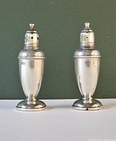 Front view of pair of sterling silver salt and pepper shakers showing their shape and condition