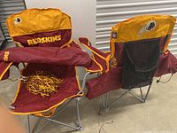 Two folded Washington Redskins branded folding chairs with maroon and yellow fabric and attached mesh storage bags.