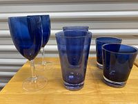 Set of six blue acrylic glasses: 2 wine glasses, 2 high drinking glasses, and 2 small tumblers
