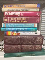 Top view of eight books stacked, including titles on running, nutrition, diet, bed and breakfast cooking, and annual cooking magazine.