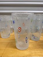 Close view of a single glass showing the textured, seeded bubble glass with colorful millefiori flowers embedded.