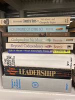 Photo shows stacked books including self help, reference, and thriller novels, condition visible is good with no mold or mildew.