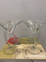 Four Libbey Bravura Martini Glasses on top of their original box showing twisted stem design and clear glass material.